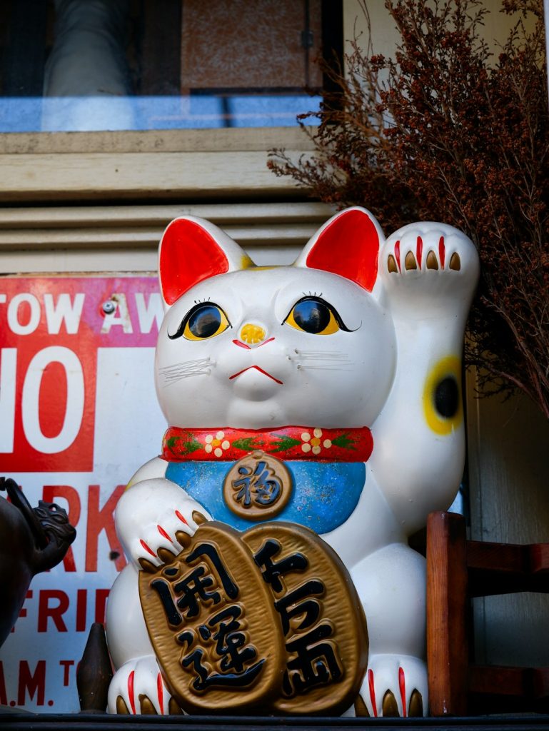 a white cat statue sitting on top of a shelf